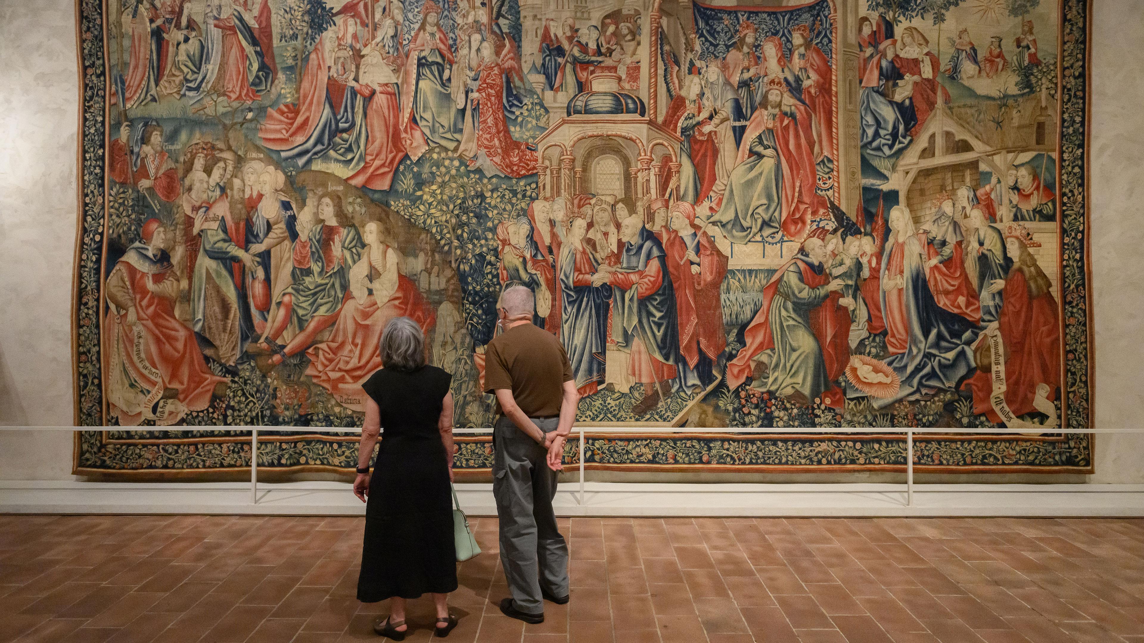 two visitors face a floor to ceiling medieval tapestry