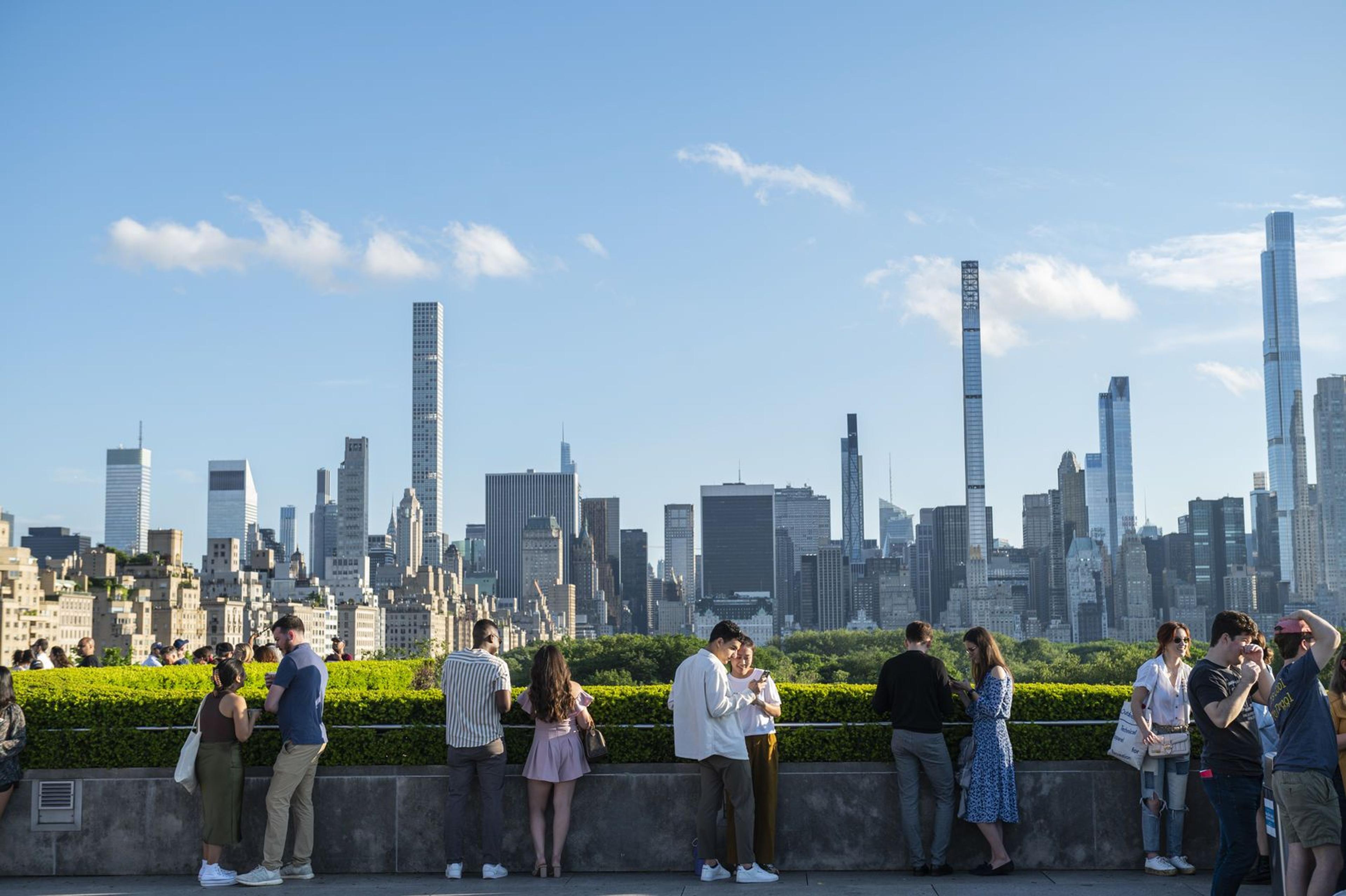 Visitors stand on a rooftop overlooking the New York City Skyline.