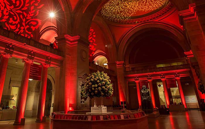 A bouquet stands in grand room with arched ceilings lit up in red